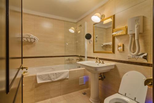 een badkamer met een toilet, een wastafel en een bad bij Hotel Snagov Club in Snagov