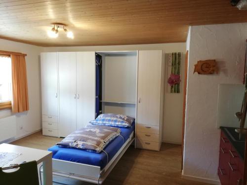 um quarto com uma cama com lençóis azuis e armários brancos em Ferienwohnung Casa Ursina em Sedrun