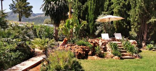 a garden with two chairs and an umbrella at Roca Verde, Boutique Bed & Breakfast - Adults only in Alhaurín de la Torre