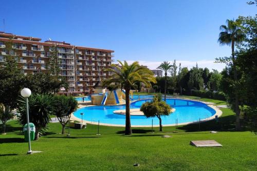 une grande piscine dans un parc planté de palmiers dans l'établissement Benalmádena estudio JJupiter 250 m del mar con vistas al mar piscinas, à Benalmádena