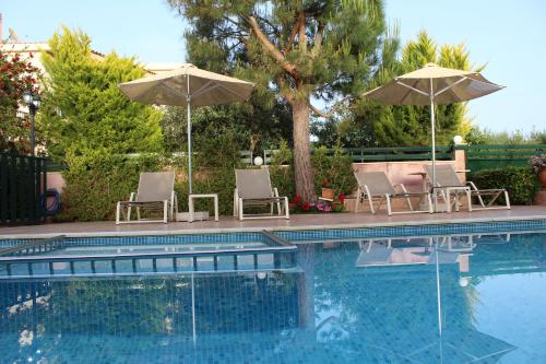 a swimming pool with two umbrellas and two chairs at Villa Alimedon in Almirida