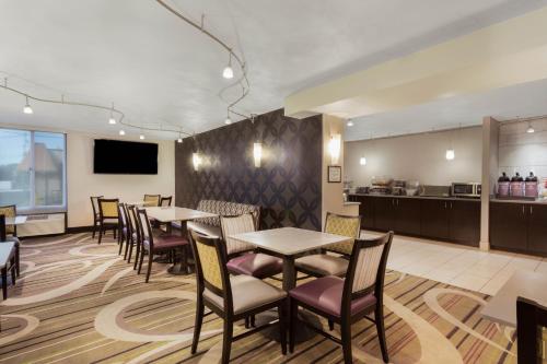 a restaurant with tables and chairs and a kitchen at La Quinta Inn by Wyndham Binghamton - Johnson City in Johnson City
