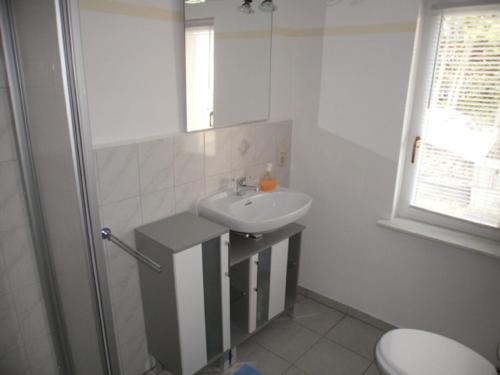 a white bathroom with a sink and a toilet at Ferienhaus Monika in Mursewiek