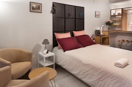 um quarto com uma cama com almofadas vermelhas e uma cadeira em Le Repaire - lescapade-medievale Sarlat em Sarlat-la-Canéda