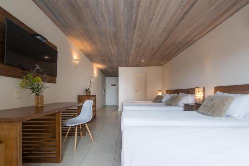 a hotel room with two beds and a desk and a tv at La Pedrera Small Hotel & Spa in Búzios