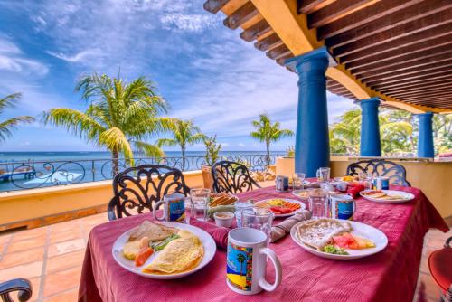 a table with plates of food and the ocean in the background at Caribe Tesoro in West Bay