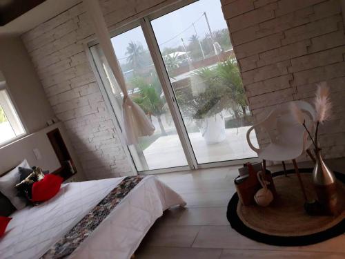 Un dormitorio con una cama y una ventana grande. en Maison charmante au Moule avec jacuzzi, en Le Moule