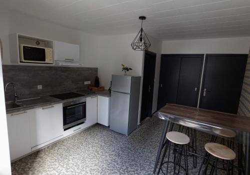  La cuisine est équipée de placards blancs et d'un réfrigérateur. dans l'établissement Villa Jean Julien - Le Sancy - Appartement T3 - 65m2 - 8 personnes, à Le Mont-Dore