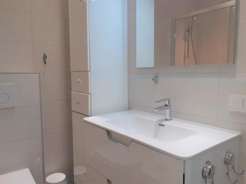 W białej łazience znajduje się umywalka i lustro. w obiekcie FH COCOLISO II w Altei