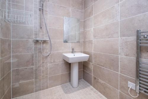 La salle de bains est pourvue d'un lavabo et d'une douche. dans l'établissement Three Tuns Apartments - Hazel, à Pettistree