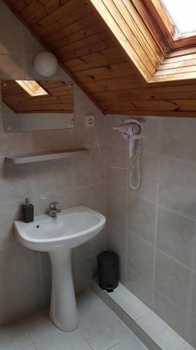 ein Badezimmer mit einem weißen Waschbecken und einer Holzdecke in der Unterkunft Szatmári Vendégház in Badacsonytomaj