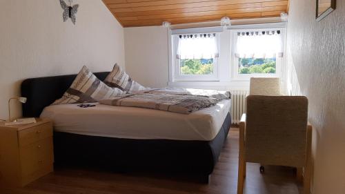 uma cama num quarto com duas janelas em Haus im Strycktal em Willingen