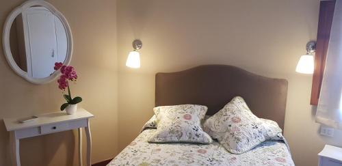 a bedroom with a bed with two pillows and a mirror at Atico Mirador Rualeira in Combarro