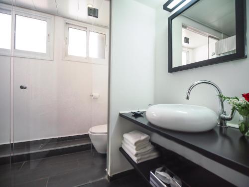 a bathroom with a sink and a toilet and a mirror at Dizengoff Avenue Boutique Hotel in Tel Aviv