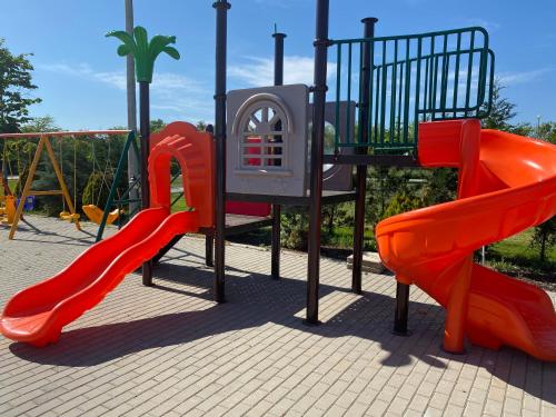 a playground with two red slides and a play structure at Resort Plaza Lake in Rojiştea