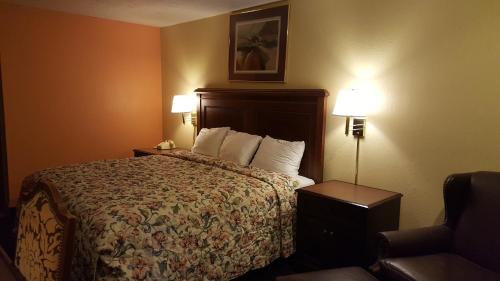 a hotel room with a bed and two lamps and a chair at Garden Inn and Extended Stay in Shepherdsville