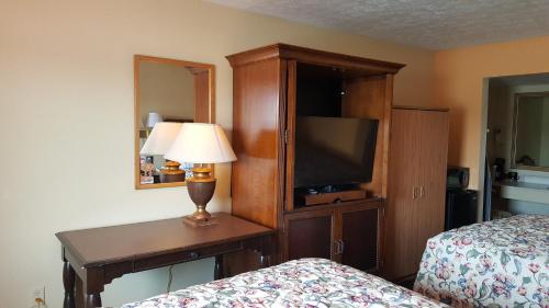 a hotel room with a tv and a bed and a lamp at Garden Inn and Extended Stay in Shepherdsville