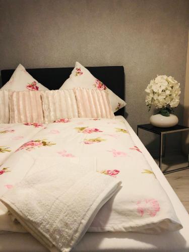 a bed with a white blanket and pink flowers on it at Carla Maria S Hause in Gammertingen