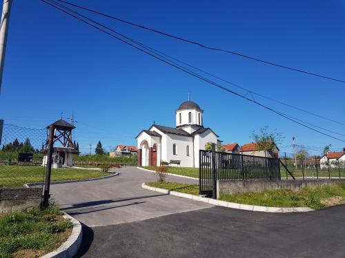 a white church with a tower on a street at VILA PEKEČ in Mala Moštanica