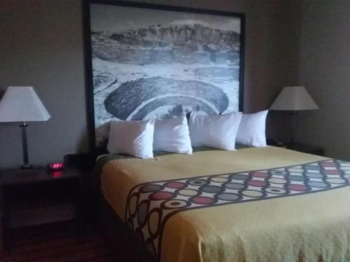 a hotel room with a bed with a large painting on the wall at Super 8 by Wyndham Taos in Taos