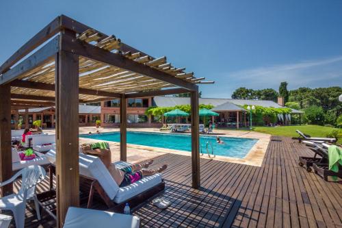 a pool with lounge chairs and a wooden pergola at Tennis Ranch Pinamar in Pinamar