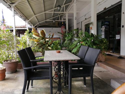 einem Tisch mit vier Stühlen vor einem Gebäude in der Unterkunft Rasa Motel in Batu Feringgi