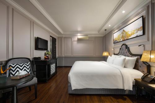 ハノイにあるImperial Hotel & Spaの白い大型ベッド1台、デスクが備わる客室です。