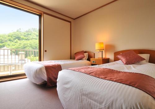 a hotel room with two beds and a large window at Uematsuya in Ueda