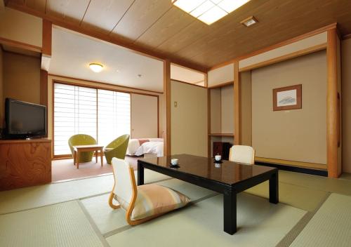 a living room with a table and chairs and a television at Uematsuya in Ueda