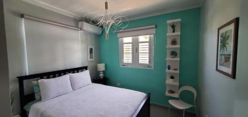 a bedroom with a white bed and a green wall at Palmeras Del Mar in Isabela