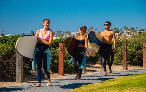 three people walking down a sidewalk with their surfboards at California Dreams Hostel - Pacific Beach in San Diego
