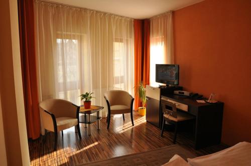 a hotel room with a desk and chairs and a television at Penzion Beryl in Košice