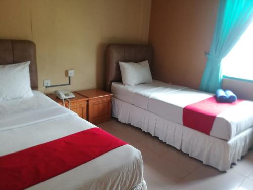 a hotel room with two beds and a window at Hotel Formosa Jambi in Paalmerah