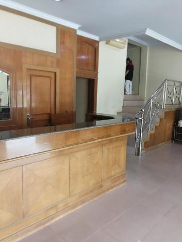a lobby with a wooden counter and a staircase at Hotel Formosa Jambi in Paalmerah