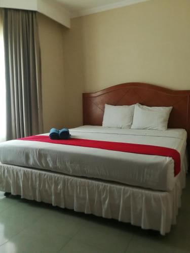 a bedroom with a large bed with a wooden headboard at Hotel Formosa Jambi in Paalmerah