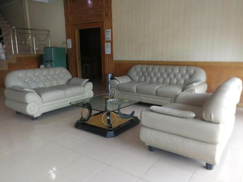 a living room with two couches and a coffee table at Hotel Formosa Jambi in Paalmerah