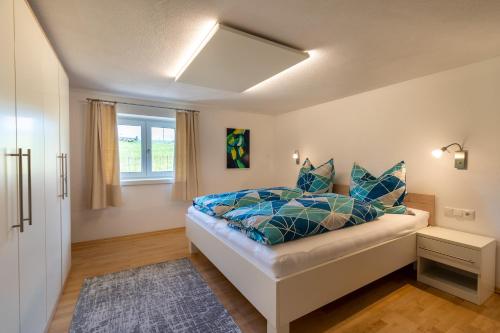 Un dormitorio con una cama con almohadas azules y una ventana en Ferienwohnung "Florin" en Ofterschwang