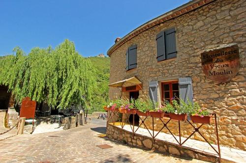 um edifício de pedra com caixas de flores ao lado em Hostellerie du Vieux Moulin em Duilhac