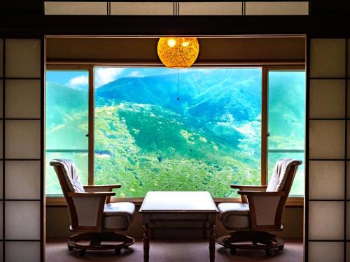 uma sala com uma mesa e cadeiras e uma grande janela em Shirayunoyado Yamadaya Hakone Gora em Hakone
