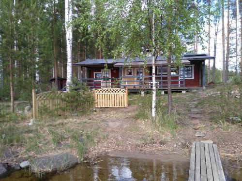eine Hütte im Wald mit einem Teich davor in der Unterkunft Takalahti Lodge in Puumala