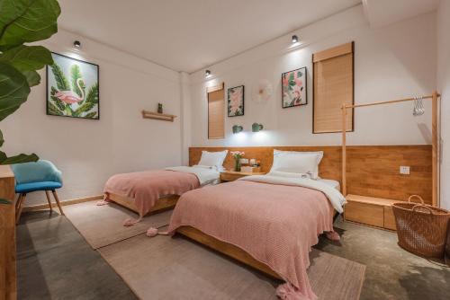a bedroom with two beds and a table and a chair at Shang Shan ruo shui 大理上山若水客栈 in Dali