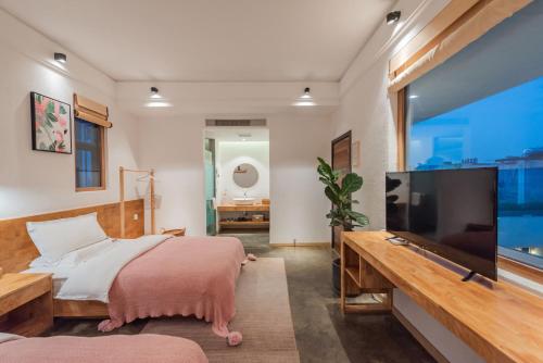 a bedroom with a bed and a flat screen tv at Shang Shan ruo shui 大理上山若水客栈 in Dali