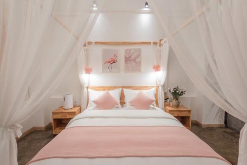 a bedroom with a canopy bed with pink pillows at Shang Shan ruo shui 大理上山若水客栈 in Dali