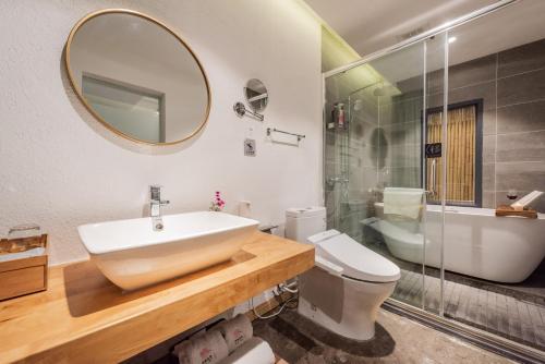 a bathroom with a sink and a toilet and a mirror at Shang Shan ruo shui 大理上山若水客栈 in Dali