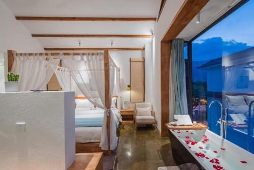 a bedroom with a bed and a large window at Shang Shan ruo shui 大理上山若水客栈 in Dali
