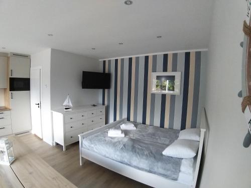 a bedroom with a bed and a dresser and a television at Przystań na Zagórzu - Apartamenty nad jeziorem in Drezdenko
