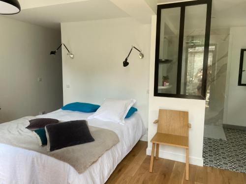 een slaapkamer met een bed, een stoel en een spiegel bij Cocon en lisière de forêt in Bourron-Marlotte