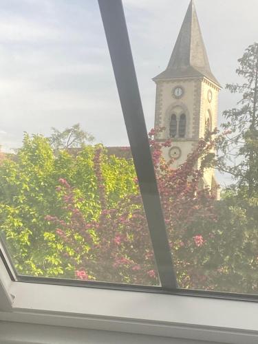 a view of a church with a clock tower at Cocon en lisière de forêt in Bourron-Marlotte