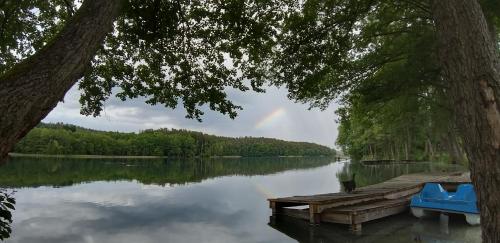 a dock on a lake with a rainbow in the sky at Przystań na Zagórzu - Apartamenty nad jeziorem in Drezdenko