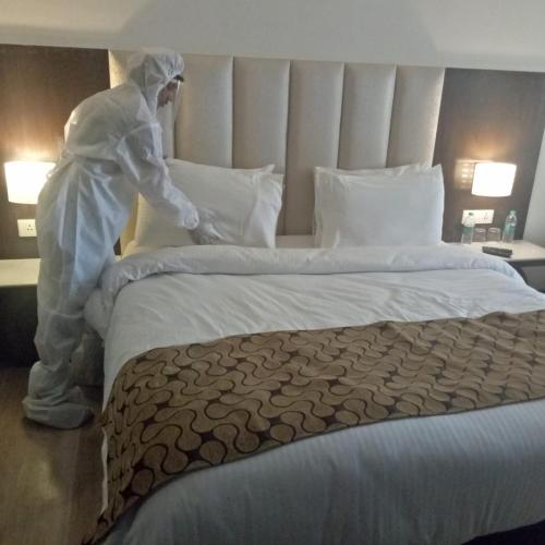 a person in a white suit making a bed at Souvenir Jaipur in Jaipur